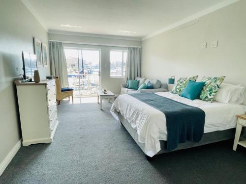 a bedroom with a large bed and a couch at Port Edge - Ships Bell, Port St Francis Bay in St Francis Bay