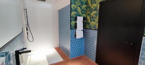 a bathroom with blue tiled walls and a black door at KONCEPT HOTEL International in Cologne