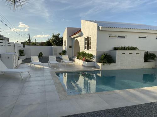 a patio with a pool and chairs and a house at Movida Inn Aruba in Palm-Eagle Beach