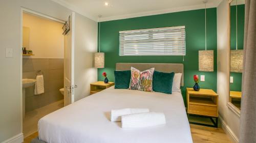 a bedroom with a large bed and a green wall at Hout & About Guest House in Hout Bay