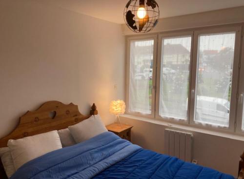 ein Schlafzimmer mit einem blauen Bett und einem Fenster in der Unterkunft Les Toiles de Mer in Wimereux