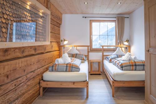 two twin beds in a room with wooden walls at Appartement Heim in Sankt Gallenkirch