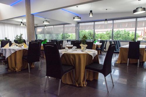 a dining room with tables and chairs and windows at Salice Resort in Marina di Schiavonea