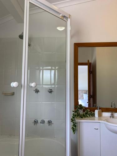 a shower with a glass door next to a sink at Luxury Top Floor Sunset Villa in Noosaville