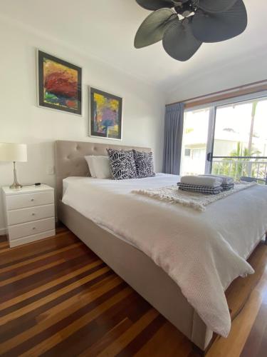 a bedroom with a large bed with a ceiling fan at Luxury Top Floor Sunset Villa in Noosaville