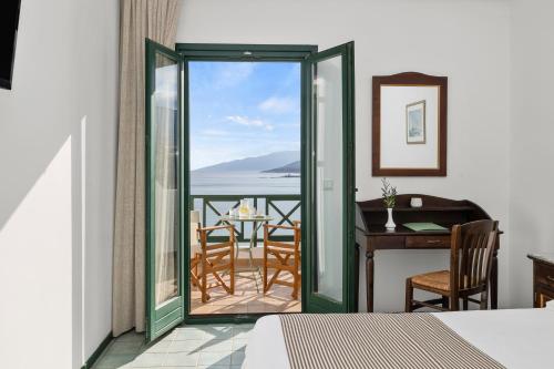 a room with a bed and a desk with a view of the ocean at Erofili Beach Hotel in Armenistis