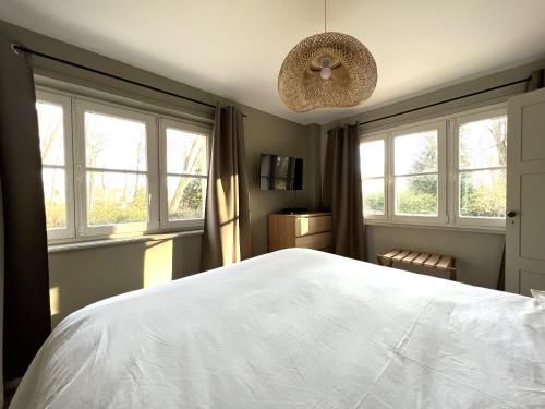 une chambre avec un grand lit blanc et des fenêtres dans l'établissement Maison en pleine forêt à 10min de Reims, à Saint-Brice-Courcelles