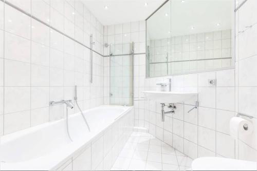 een witte badkamer met een bad en een wastafel bij Ostsee Panoramaloft in Juliusruh