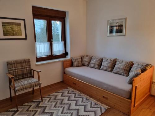 un sofá en una habitación con una silla y una ventana en Ferienwohnung Schindler, en Nittenau