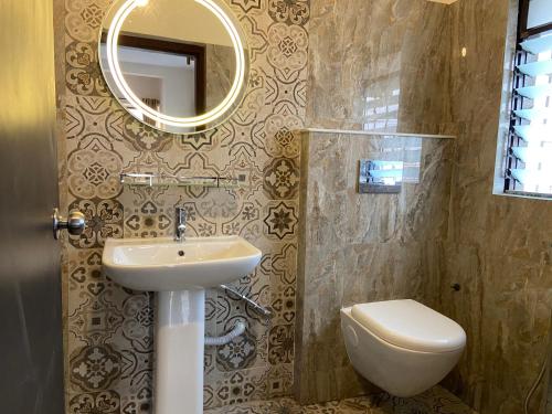 a bathroom with a sink and a toilet and a mirror at The Aster Penthouse in Kolkata