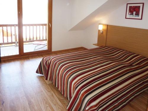 ein Schlafzimmer mit einem Bett mit einer gestreiften Decke in der Unterkunft Appartement Les Orres, 3 pièces, 10 personnes - FR-1-322-296 in Les Orres