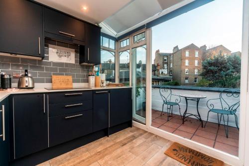 a kitchen with black cabinets and a patio with a table at Pass the Keys Modern Victorian home in London in London