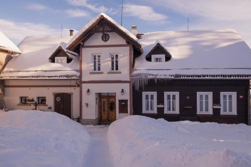 a house covered in snow with a pile of snow at Penzion Statek u Rajtrů in Bedřichov
