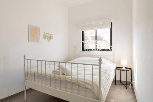 ein weißes Schlafzimmer mit einem Bett und einem Fenster in der Unterkunft סוויטת מול הבניאס in Kibbutz Snir