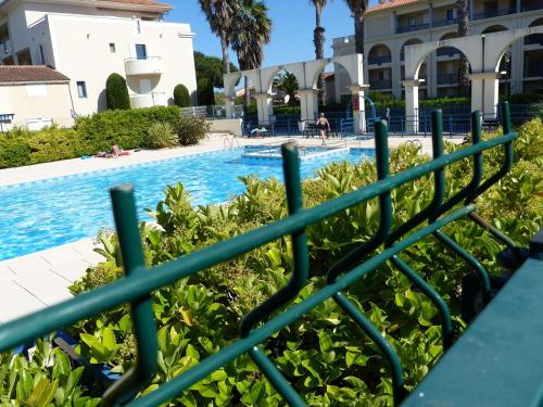 une vue de la piscine depuis la clôture d'un complexe hôtelier dans l'établissement Mazet Climatisé 3P avec Terrasse et Piscine - Le Lavandou - FR-1-308-78, au Lavandou