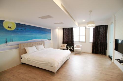 a bedroom with a bed and a painting on the wall at Key We Go Hotel 奇遇果人文旅店 in Tainan