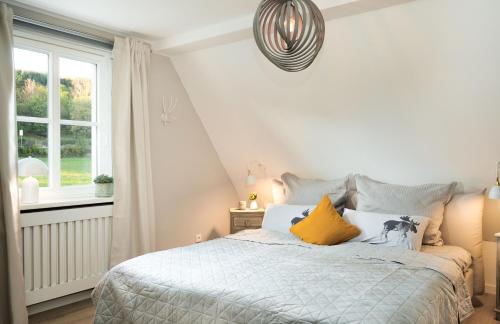 a white bedroom with a bed with yellow pillows at Villa federleicht in Medebach