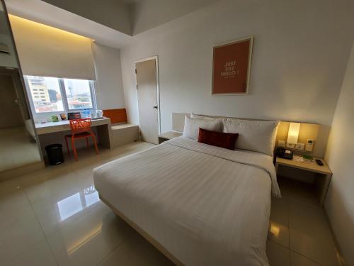Habitación de hotel con cama blanca grande y escritorio. en Zuri Express Mangga Dua en Yakarta