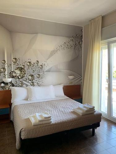 a bedroom with a bed with white pillows and a wall at Hotel President in Cervia