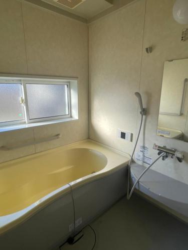 a bathroom with a tub and a window and a sink at Five Peaks Ryuoo in Shimotakai