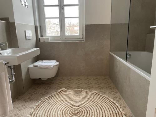 La salle de bains est pourvue d'un lavabo, de toilettes et d'une baignoire. dans l'établissement Gmund Seeliebe Premiumsuite, à Gmund am Tegernsee