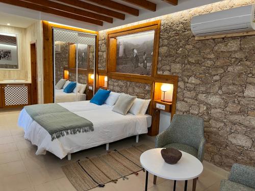 Hotel Rural Rosario Martin في بويرتو ديل روزاريو: غرفة نوم بسرير وجدار حجري