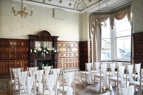 a room filled with white chairs and a chandelier at Royal Station Hotel- Part of the Cairn Collection in Newcastle upon Tyne