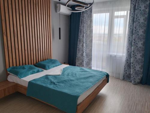 1 dormitorio con cama con sábanas azules y ventana en 1-ком VIP квартира en Kostanái