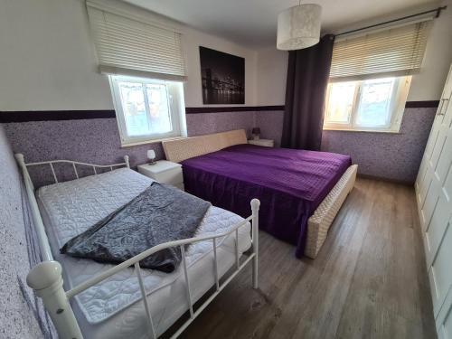 1 dormitorio con 2 camas, sábanas moradas y ventanas en Ferienwohnung Flair, en Dölzig