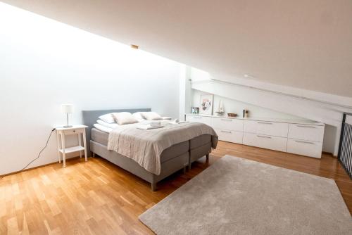 a white bedroom with a bed and a rug at 2ndhomes Unique & Spacious 2-Storey Apartment with Sauna in Helsinki