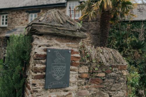 um sinal numa parede de tijolos em frente a uma casa em Sheviock Barton Bed & Breakfast em Sheviock