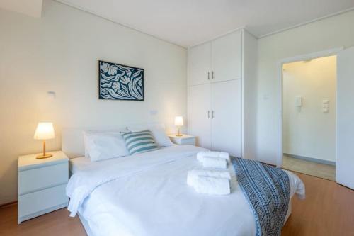 ein weißes Schlafzimmer mit einem großen weißen Bett und zwei Lampen in der Unterkunft Glyfada Center Sea View Apt in Athen