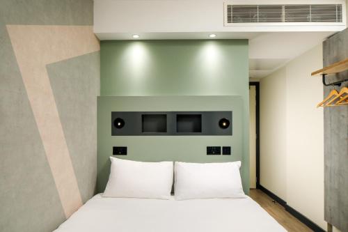 1 dormitorio con 1 cama con almohadas blancas en ibis budget Manchester Airport en Hale