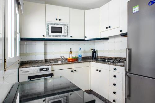 a kitchen with white cabinets and a stainless steel refrigerator at Las Sales Duplex in Moya
