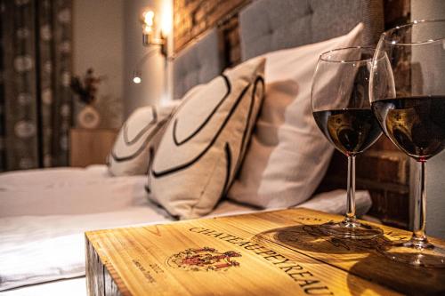 two glasses of wine on a table with a bed at Wine Apartments in Kraków