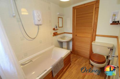 ein Badezimmer mit einer Badewanne, einem WC und einem Waschbecken in der Unterkunft Khyber Pass Cottage, Stromness - OR00332F in Stromness