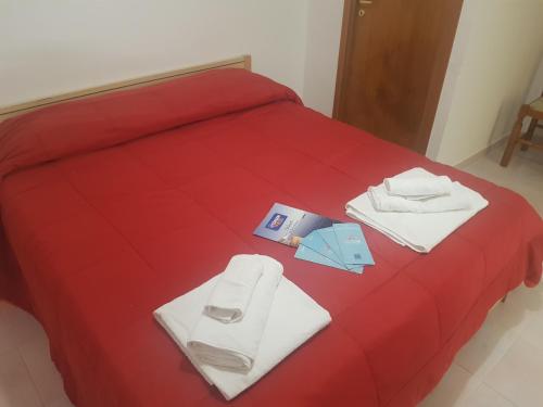 a red bed with towels and a book on it at Appartamenti Oleandri Baia Verde in Gallipoli