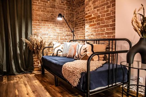 a bedroom with a bed with pillows and a brick wall at Wine Apartments in Kraków
