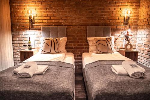 two beds in a room with a brick wall at Wine Apartments in Kraków
