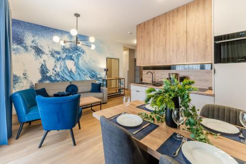 kuchnia i salon ze stołem i niebieskimi krzesłami w obiekcie Sunset Resort III, Nadmorska 100A w Grzybowie