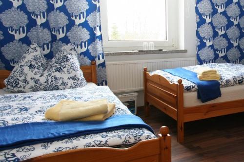 2 Betten in einem Schlafzimmer mit blauen und weißen Tapeten in der Unterkunft Waldpension Droyßig in Droyßig