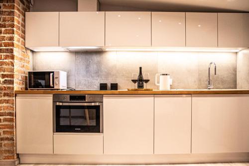 a kitchen with white cabinets and a microwave at Wine Apartments in Kraków