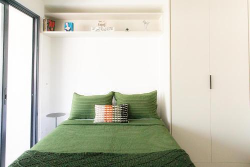 1 dormitorio con cama verde y pared blanca en Cantinho Paulista, en São Paulo