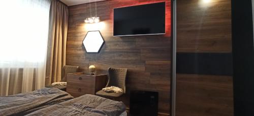 a hotel room with two beds and a flat screen tv at Апартамент Bella Casa in Beli Iskar