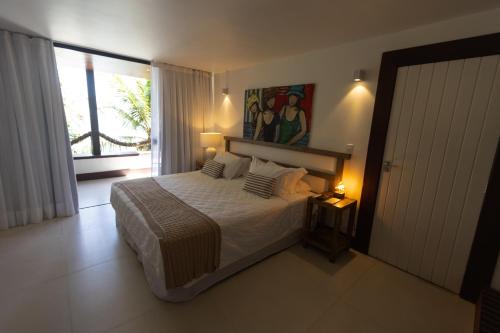a bedroom with a bed and a large window at Pousada Enseada das Garças in São Pedro da Aldeia