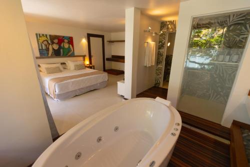 uma casa de banho com uma banheira e um quarto com uma cama em Pousada Enseada das Garças em São Pedro da Aldeia