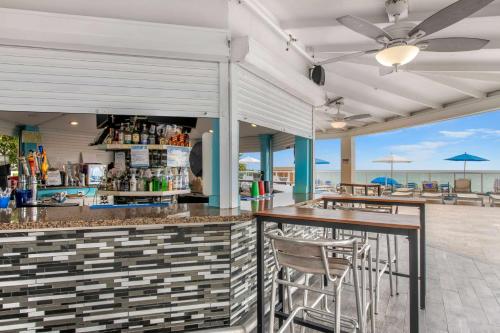 a bar with chairs and a counter with the ocean in the background at Ramada Plaza by Wyndham Marco Polo Beach Resort in Miami Beach