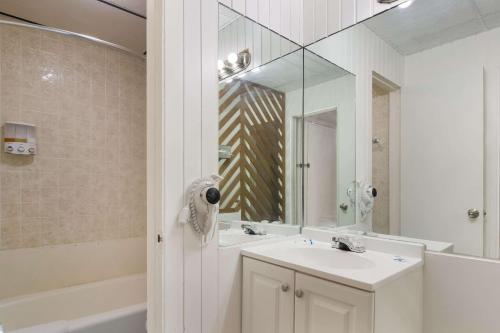 a bathroom with a sink and a mirror and a tub at Rodeway Inn & Suites Sidney Historic Downtown I-80 in Sidney