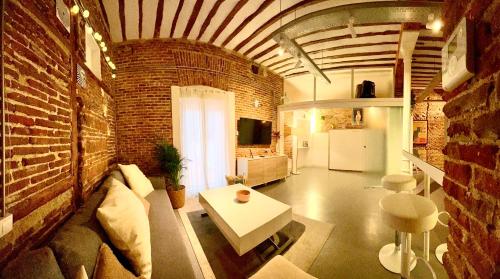 a living room with a couch and a brick wall at calle Amparo100 Red brick loft for 8 Madrid Lavapies in Madrid