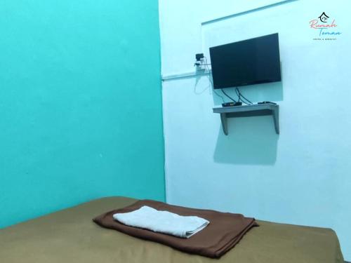 a room with a bed with a tv and a blanket at Rumah Teman Hostel in Semarang